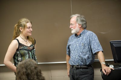 A student and a professor having a one-on-one discussion in a classroom, focused and engaged.