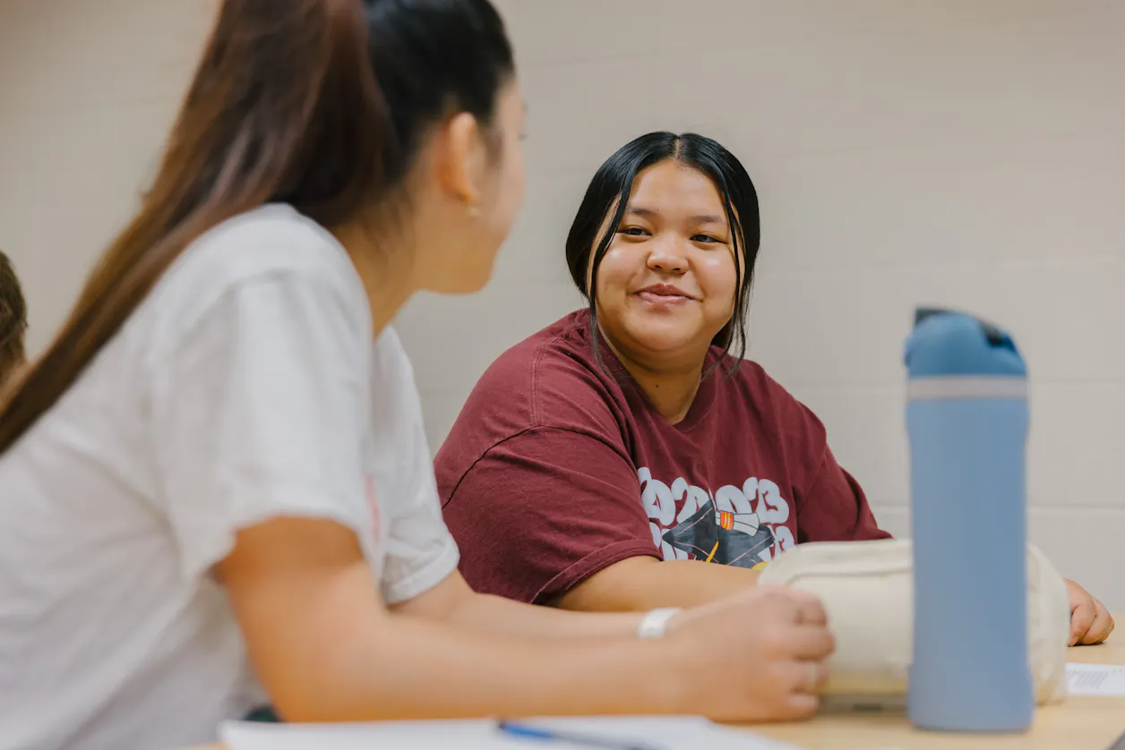 Students taking notes and listening attentively in a classroom setting. 