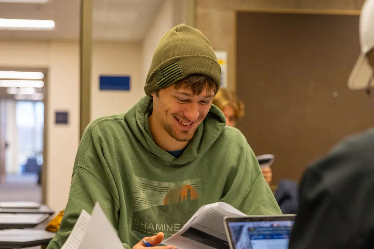 smiling student in green flag hat