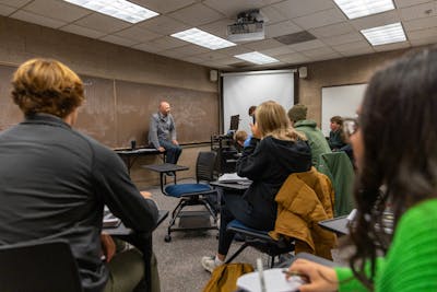 A professor lecturing a group of attentive students in a classroom, fostering an interactive learning environment.
