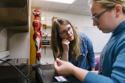 A professor guides a student through a lab exercise.