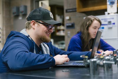 Students focus on laptops during a lab session.