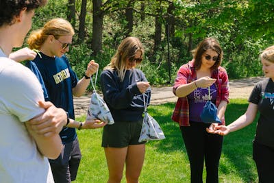 Students outside close the clasps on bags. 