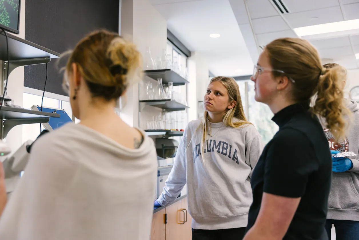 Group of students observing a display screen in a lab.