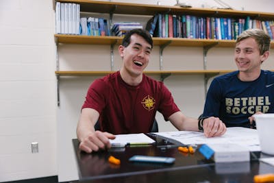 Two students studying together at a table, laughing and enjoying the learning process.