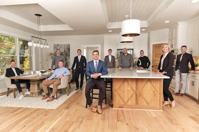 Sam Steadman '16, center, poses in the middle of his RE/MAX Results team in an open-concept kitchen.