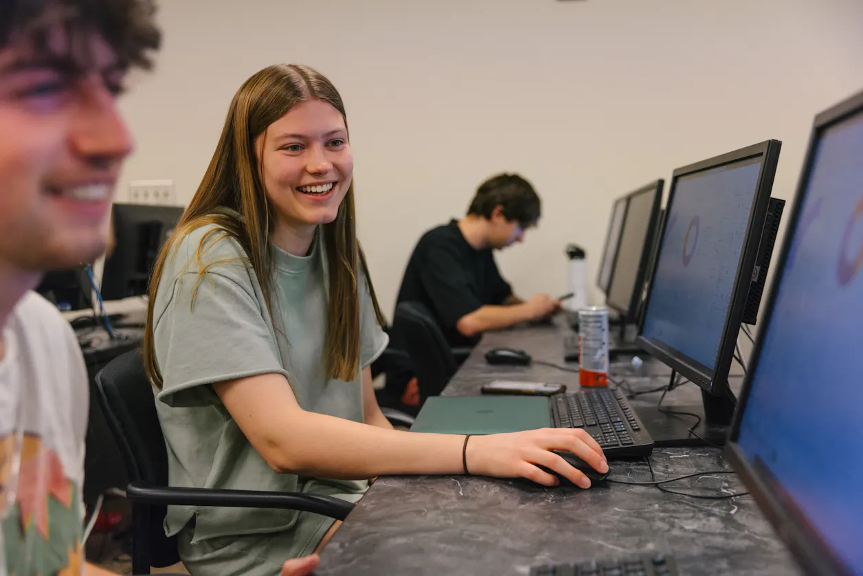 Two students working on computers in a classroom.
