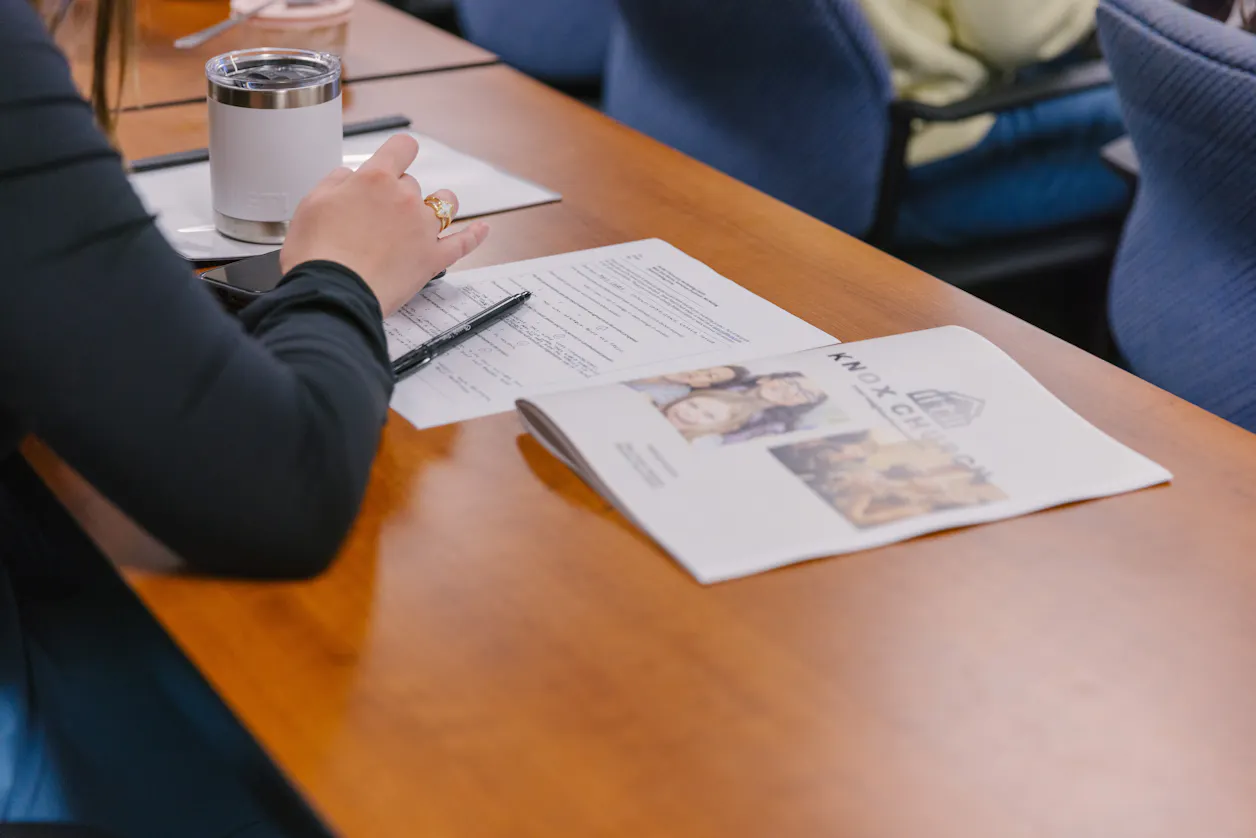 A student with a drink and notes on the table, participating in a classroom activity.