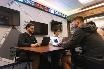 Students working in a business lab, focusing on their laptops.