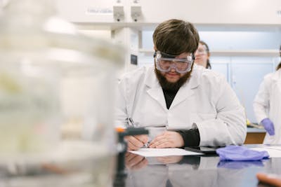 Student focused on writing notes during a lab session.