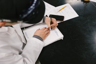 Student taking detailed notes in a lab notebook during an experiment.