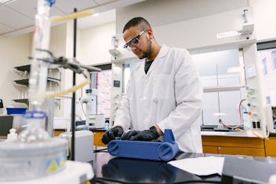 Group of students in lab coats discussing their experiment with enthusiasm.
