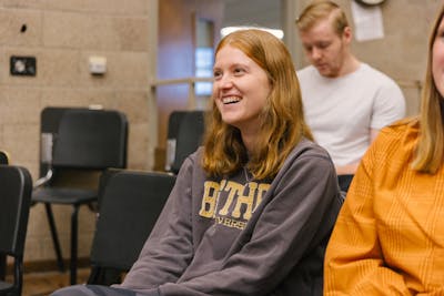 Student with long hair smiling brightly during a class activity. 