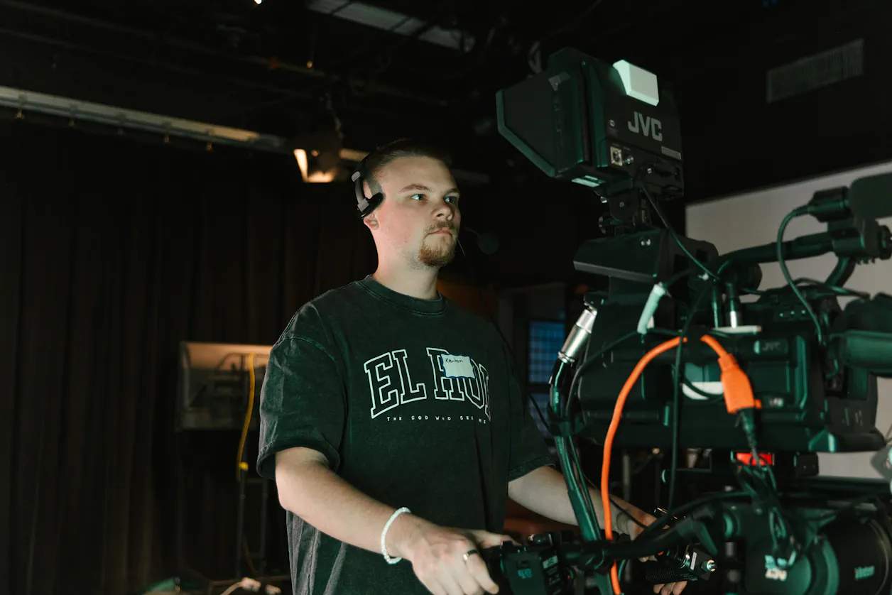 A student operating a professional video camera during a studio recording session. 