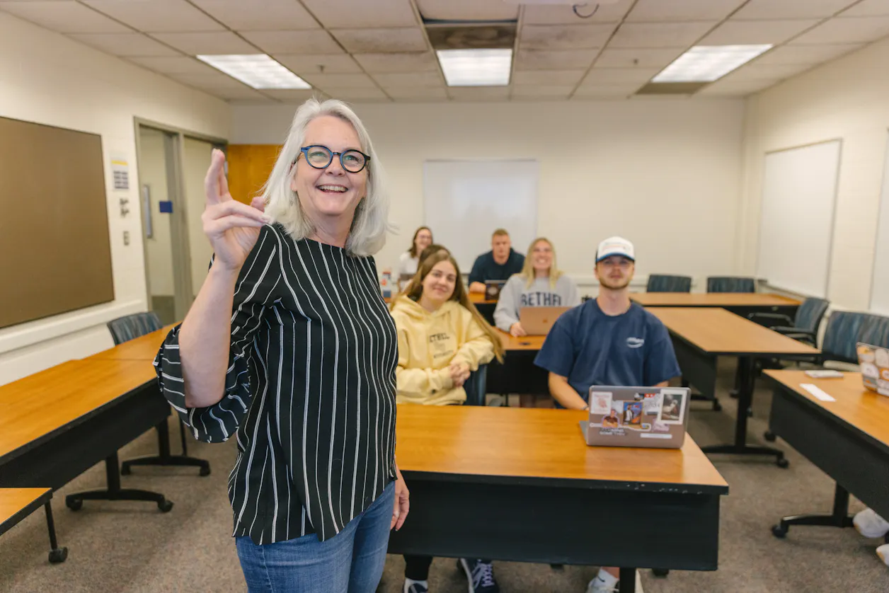 A professor posing with a classroom full of students, all smiling and engaged. 