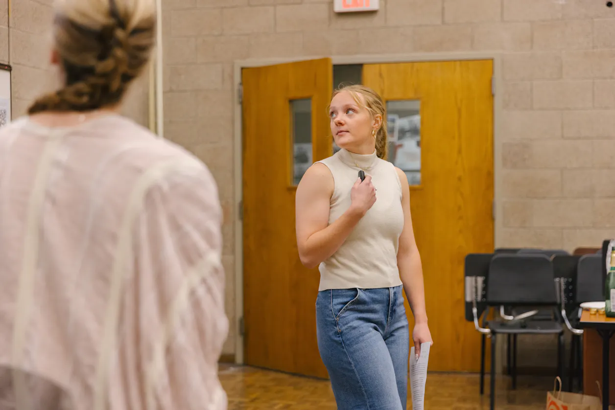 Student holding a remote, engaging in a presentation in front of classmates. 