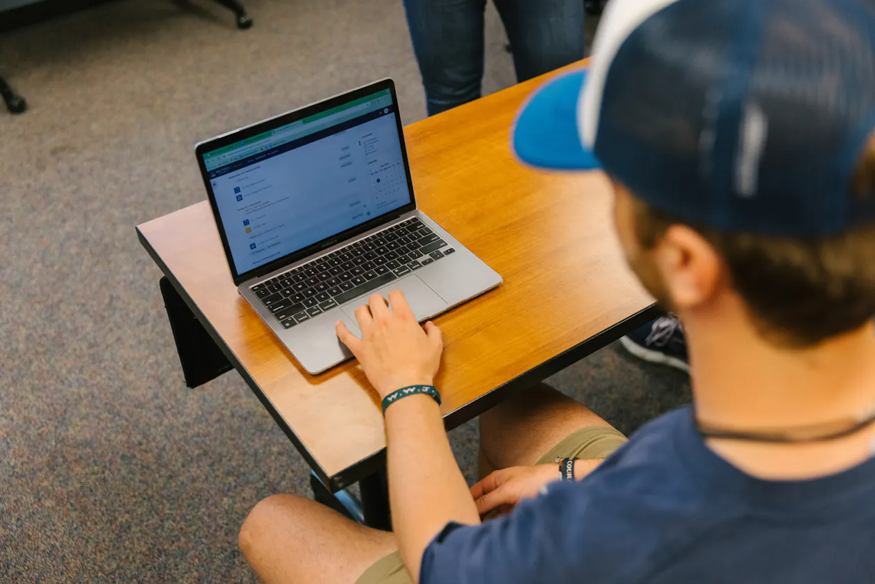 Student using a laptop, focused on an assignment in a classroom setting. 