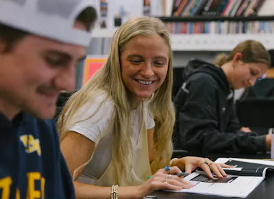 Student smiles while reviewing a visual design project with classmates.