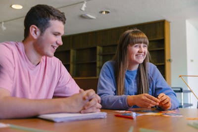 A male and female student share a laugh during a creative project session at Bethel University.