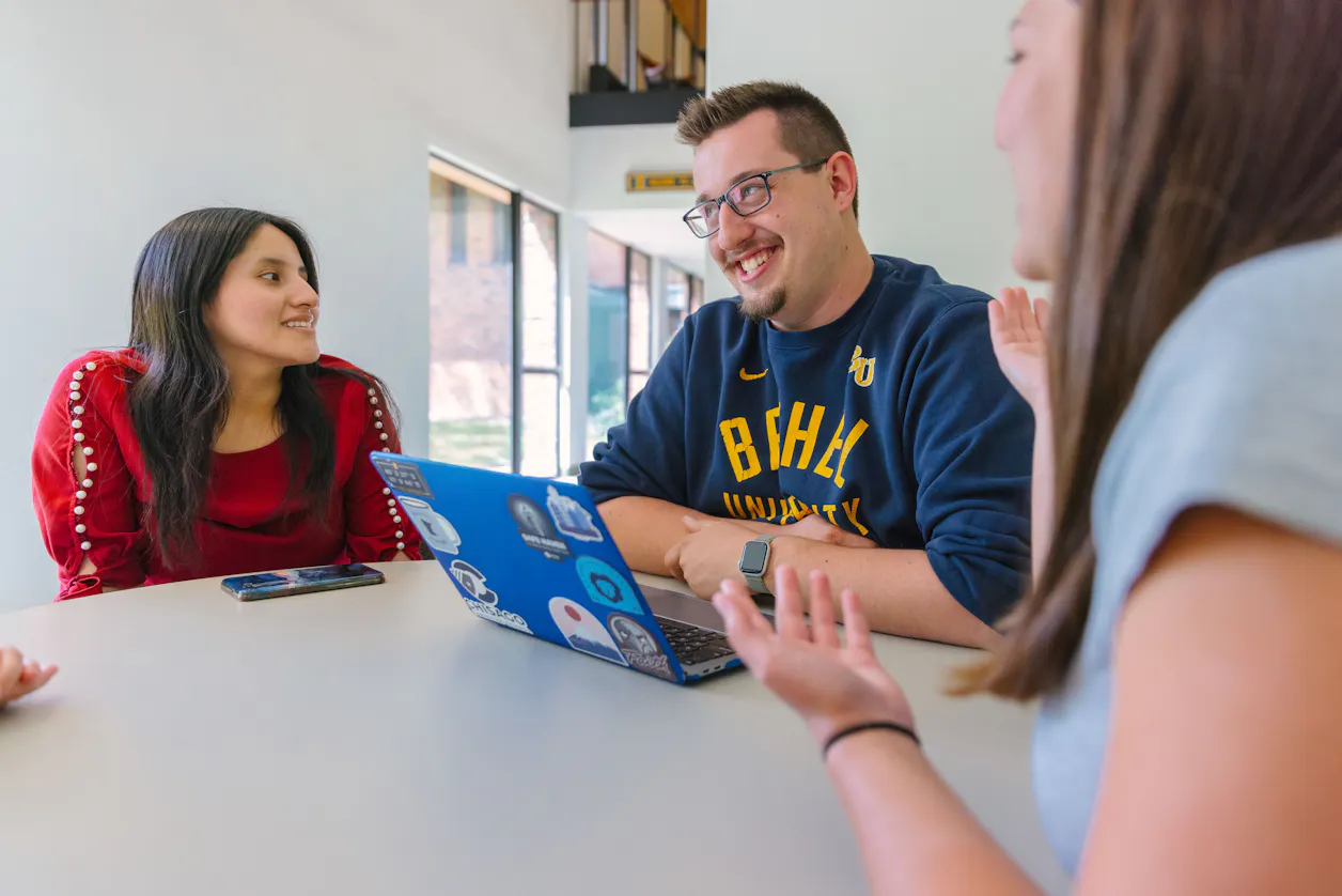A group of students engaged in a lively discussion around a table at Bethel University.
