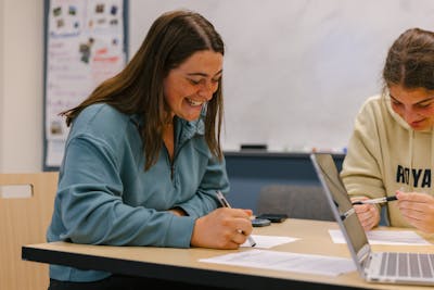 A student smiles while working on a collaborative project in a classroom at Bethel University.