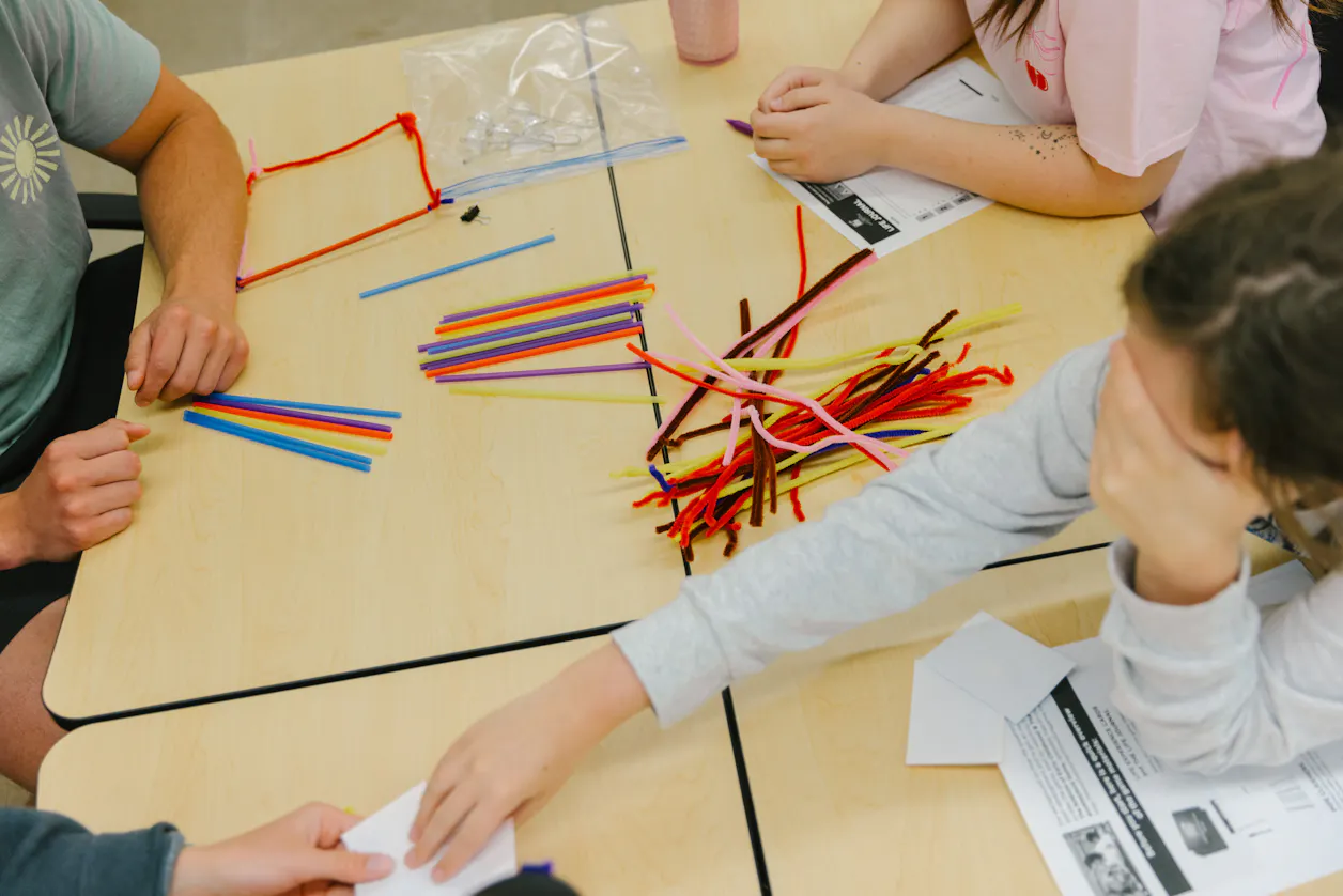Students working with colorful pipe cleaners and straws in a hands-on activity.