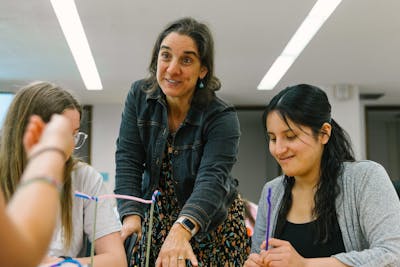 Professor engages with students using pipe cleaners during a hands-on learning activity at Bethel.