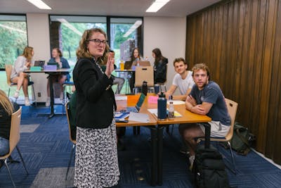 A Bethel University professor giving a lecture with a presentation displayed on the screen.