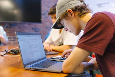 A Bethel University student focused on typing on a laptop during a group study session. 