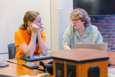 Two students are deep in conversation at a table. 