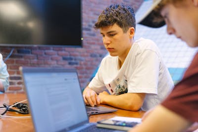 Bethel University students focused on their laptops during a study session in a classroom.