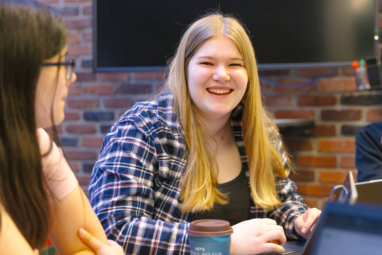 A Bethel University student smiling while engaged in a lively conversation with classmates in a study room. 