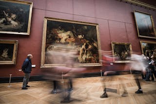 Visitors moving quickly past large paintings in an art museum, creating a blurred motion effect.