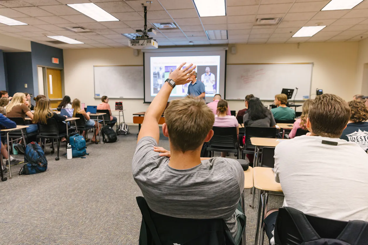 A student raises a hand to ask a question during a lecture at Bethel University.