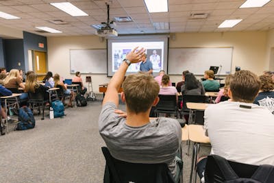 A student raises a hand to ask a question during a lecture at Bethel University.