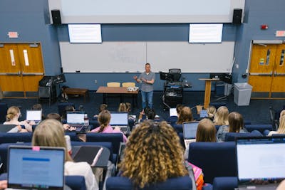 A Bethel University professor giving a lecture to students in a large classroom.