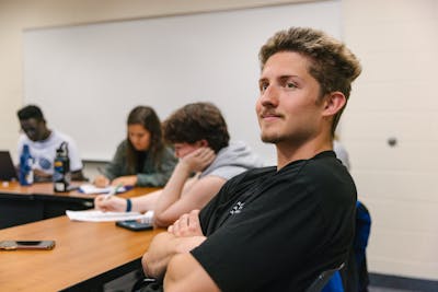 A Bethel University student smiling and participating in a classroom discussion.