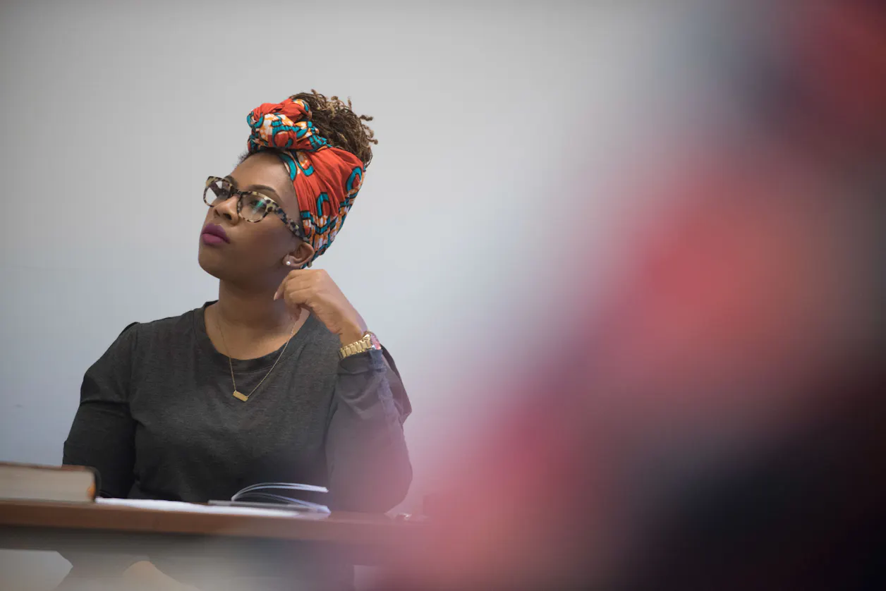A student thoughtfully listens, wearing a colorful headwrap, during a language class.
