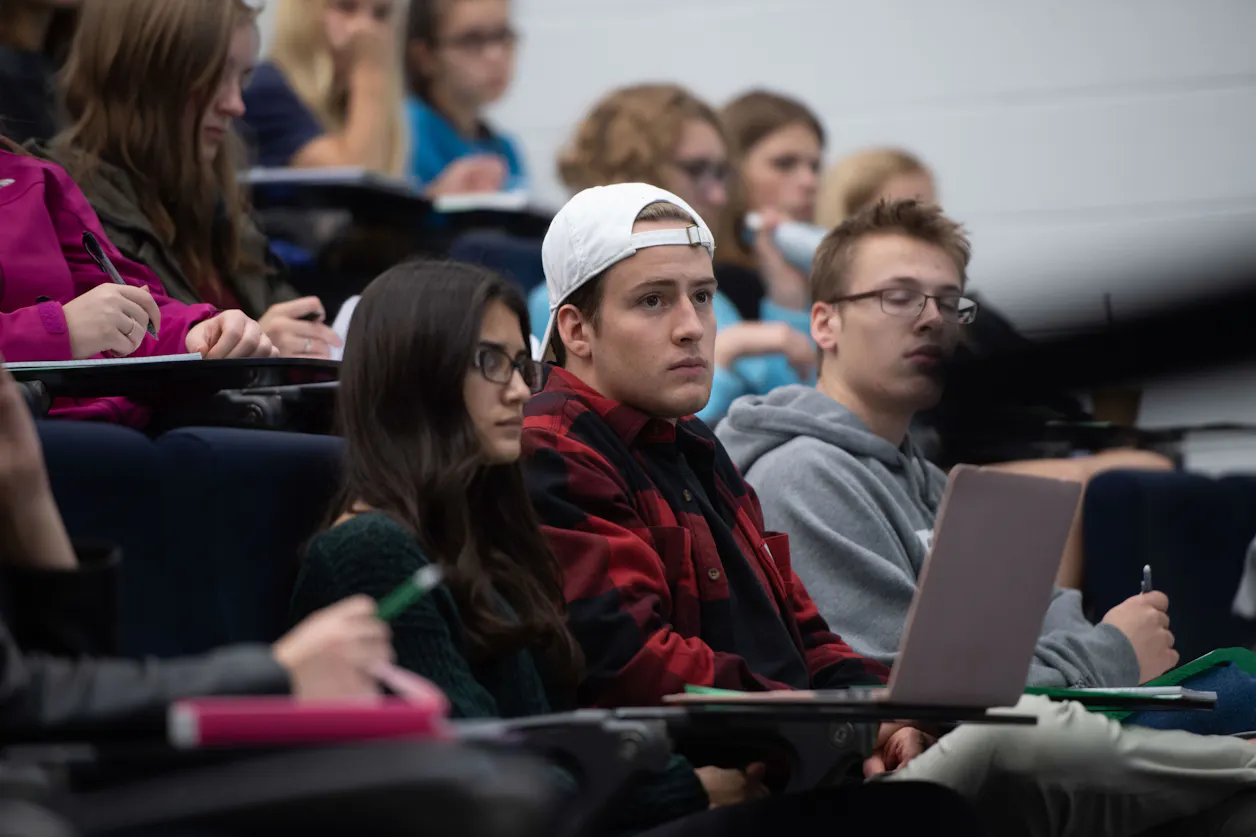 Students in a lecture hall, attentively listening and taking notes during a language class. 