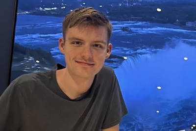 Student Michael Opheim poses on a balcony overlooking overlooking a waterfall.