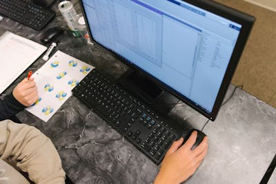 Overhead view of a student working on a computer, analyzing data and diagrams.