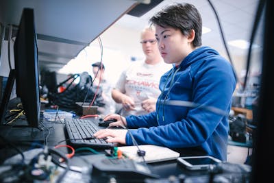 Focused student working on a computer project in a tech lab at Bethel University.