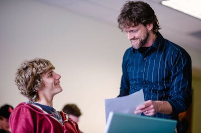 Professor smiles while talking to a student, fostering a positive learning environment.