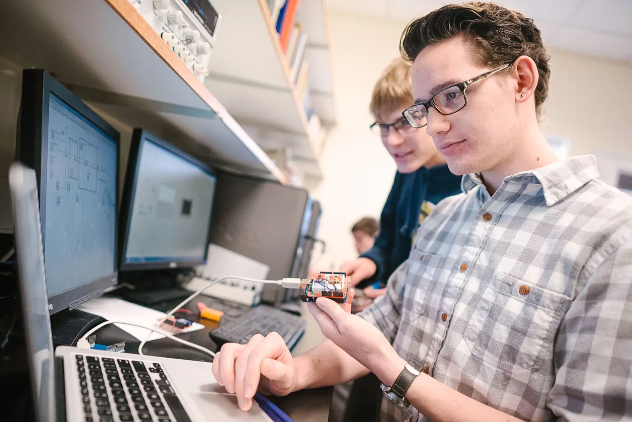 Two students working together on a project, using computers and lab equipment.