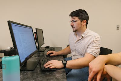 Student coding on a computer, concentrating on their work at Bethel University.