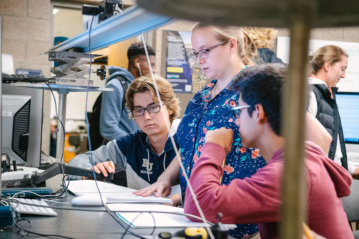 Professor engaging with students while drawing complex diagrams on a board.