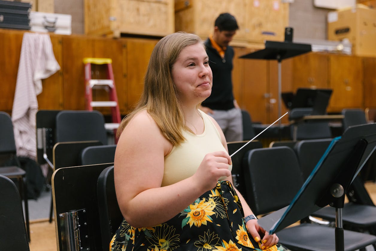 A Bethel student in a music rehearsal room, holding a conductor's baton with a focused expression.