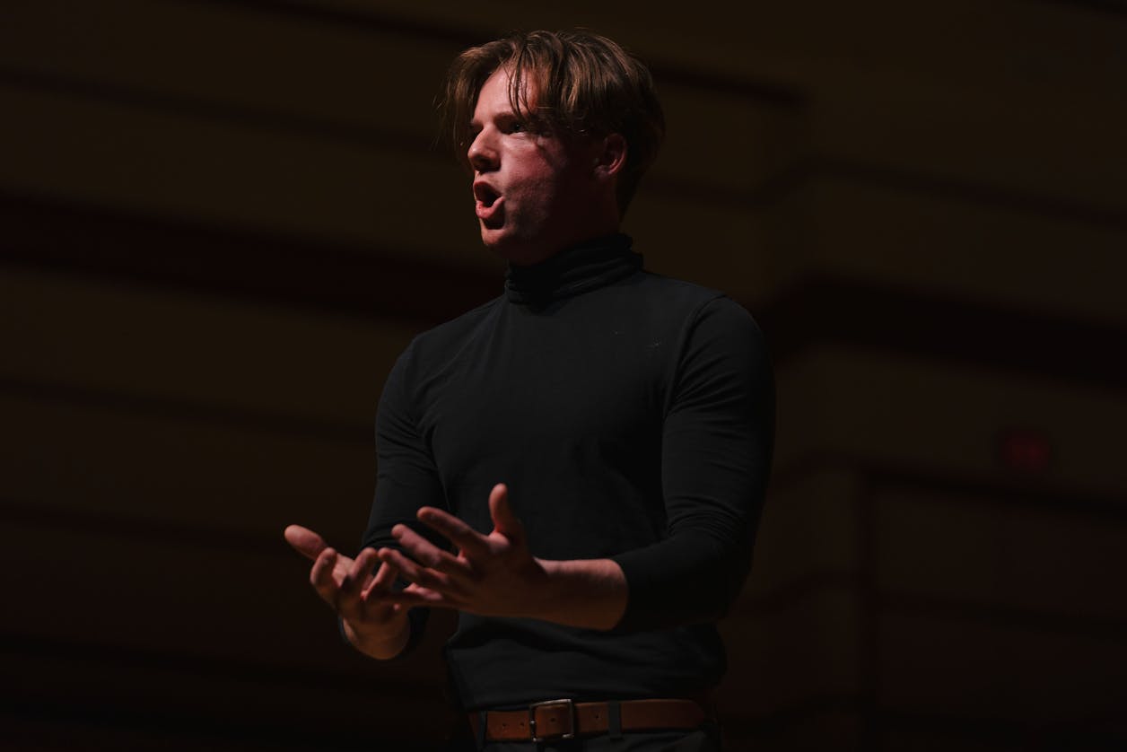 A student passionately singing on stage during a performance.
