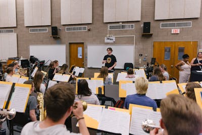 A professor leading a band class, students playing various instruments.