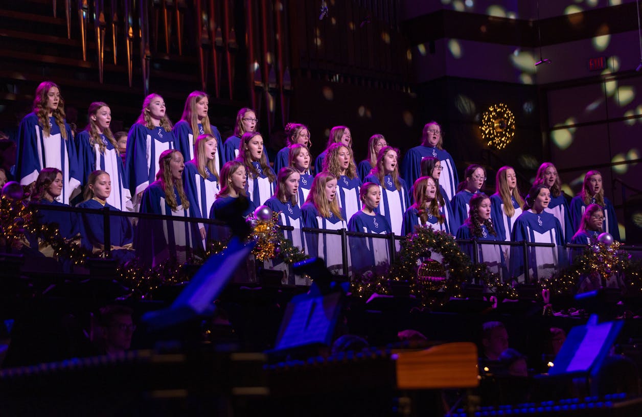 A choir of students singing in unison during a beautifully lit concert.